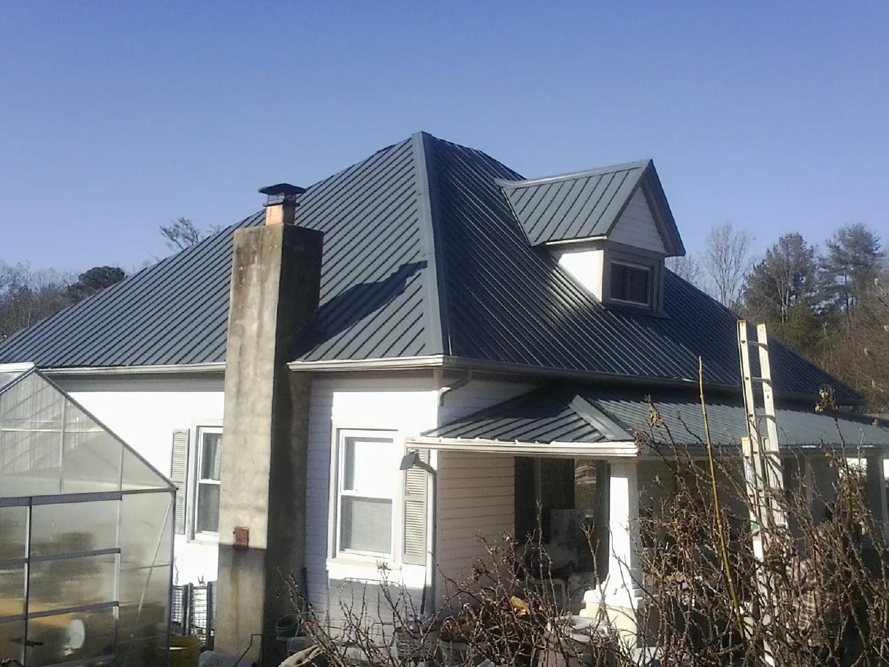 Dark blue standing seam metal roof on a white farmhouse with dormer — Slate & Tile Roof Repair by Roofing Brothers in Neshanic Station