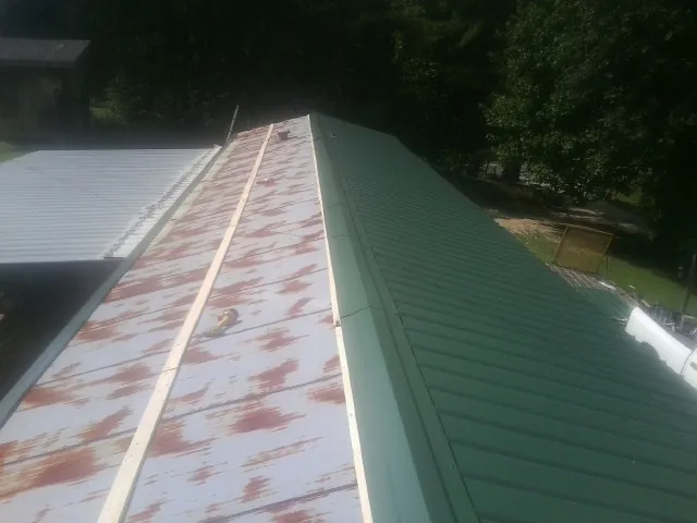 Old rusted panels beside newly installed green metal roofing — Wind Damage Roof Repair by Roofing Brothers in Neshanic Station