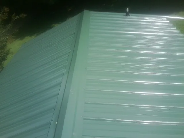 New green metal panels meeting at the ridge of a roof — Flat Roof Repair work by our crew in Neshanic Station