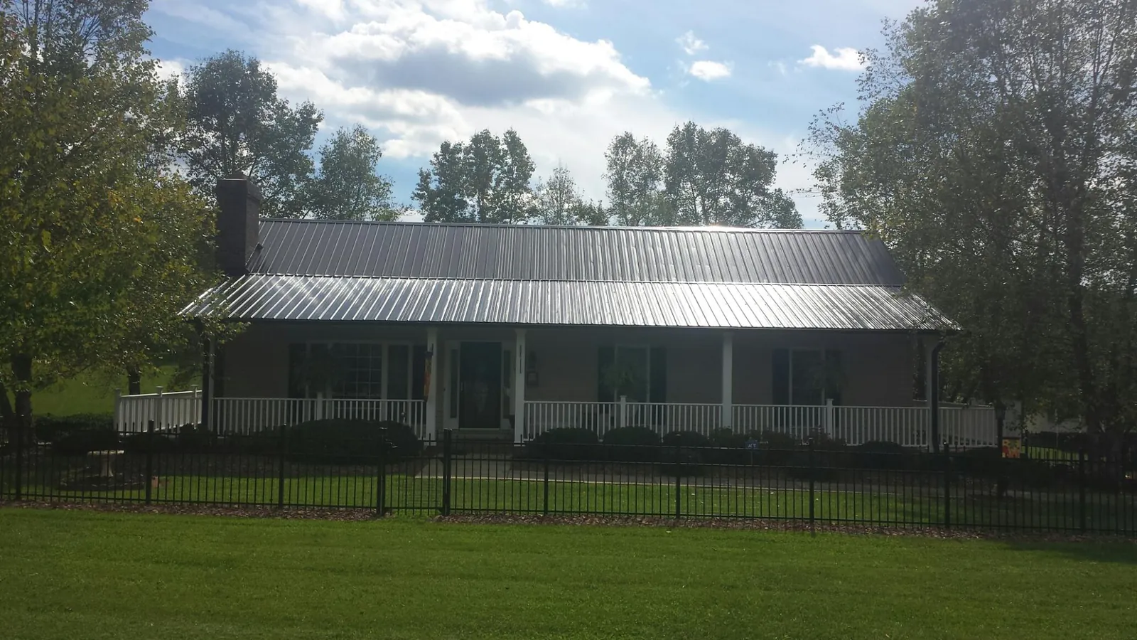 Gray metal roof on a brick ranch with a full width front porch — Gutter Guard Installation work by our crew in Neshanic Station