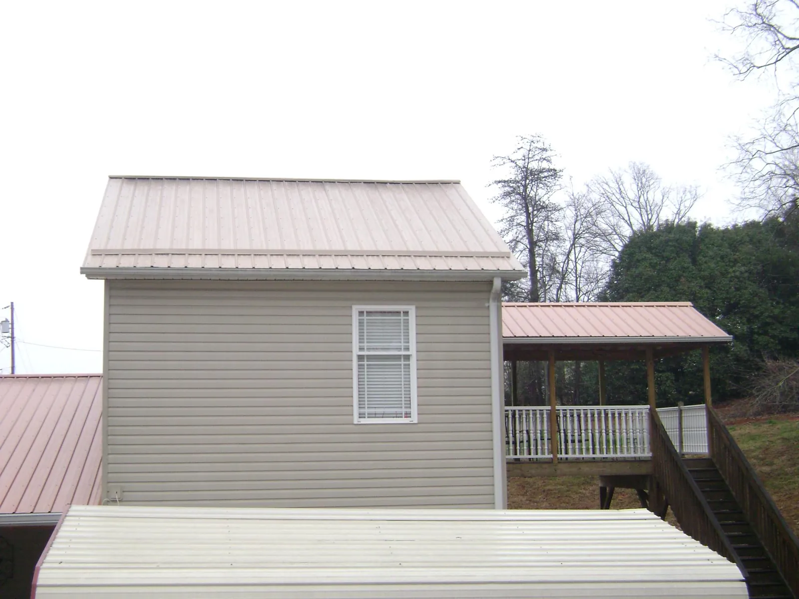 Tan metal roofs on a two story addition and attached porch, from a Roof Replacement job in Neshanic Station