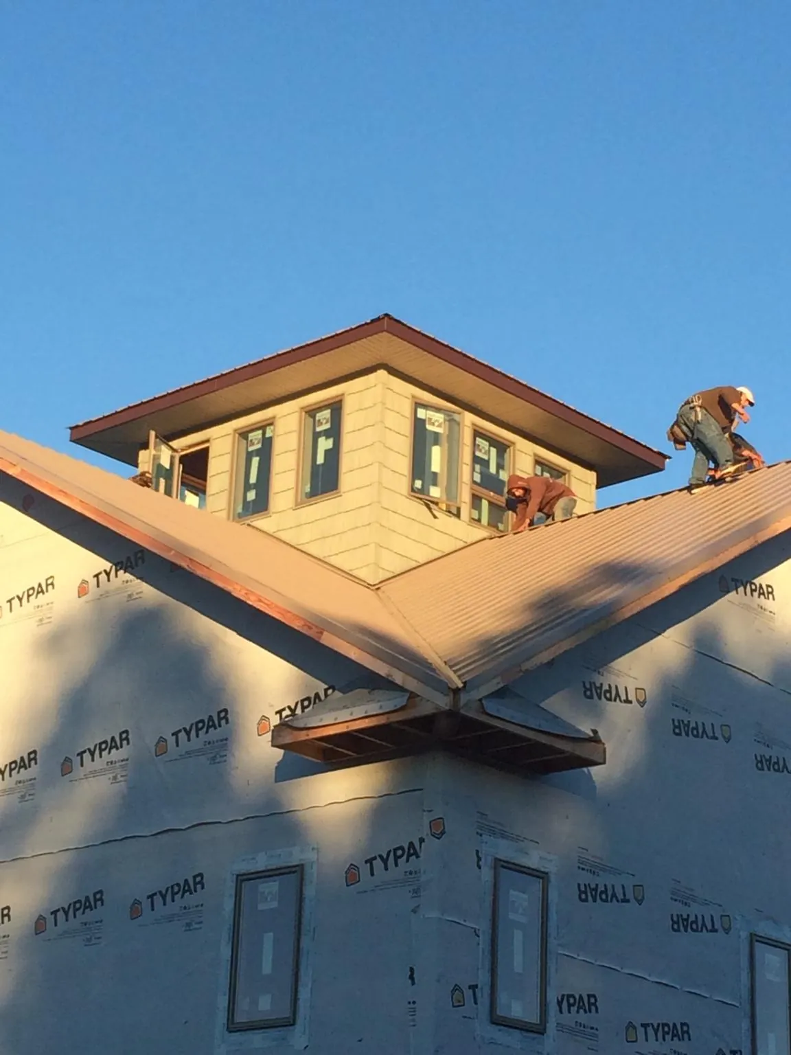 Roofers working around a rooftop cupola on a new metal roof at sunset — Roof Waterproofing in Neshanic Station by Roofing Brothers